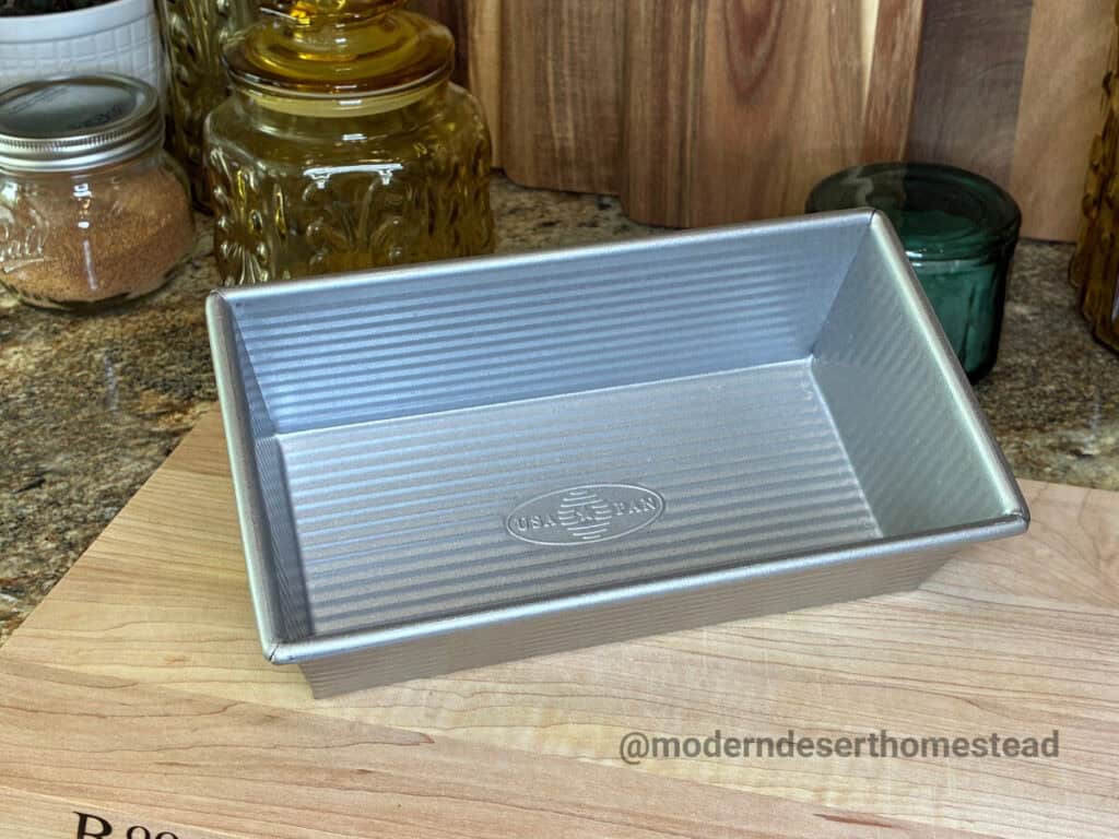 USA Pan 1.25 lb loaf pan on a wooden cutting board in a home kitchen