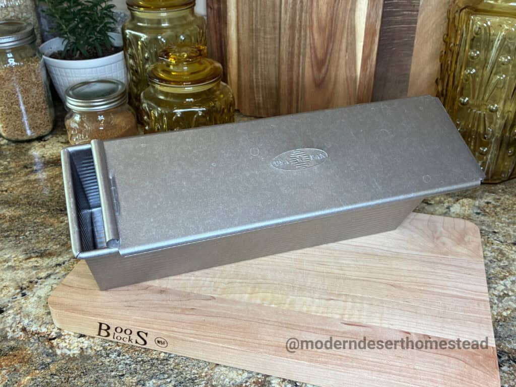 USA Pan 13 x 4 pullman pan on a wooden cutting board in a home kitchen